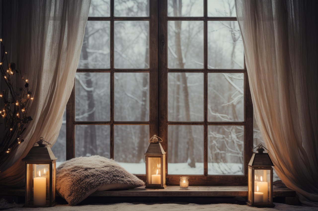 Rebord de fenêtre cocooning avec coussins, bougies et guirlande lumineuse de Noël
